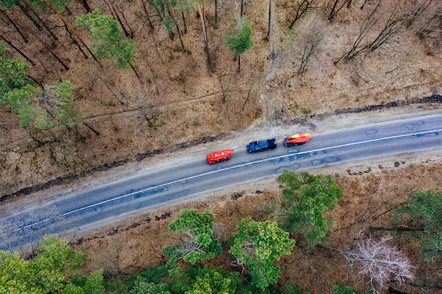 Plusieurs voitures avec kayaks sur galerie de toit conduisant sur la route parmi les arbres